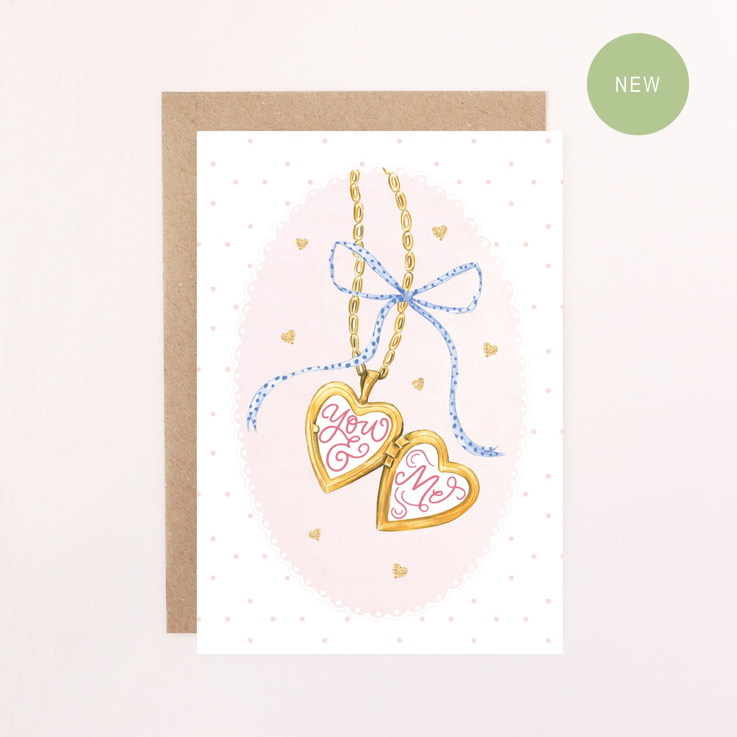 Greeting card with heart-shaped locket and 'You & Me' text on a pink background