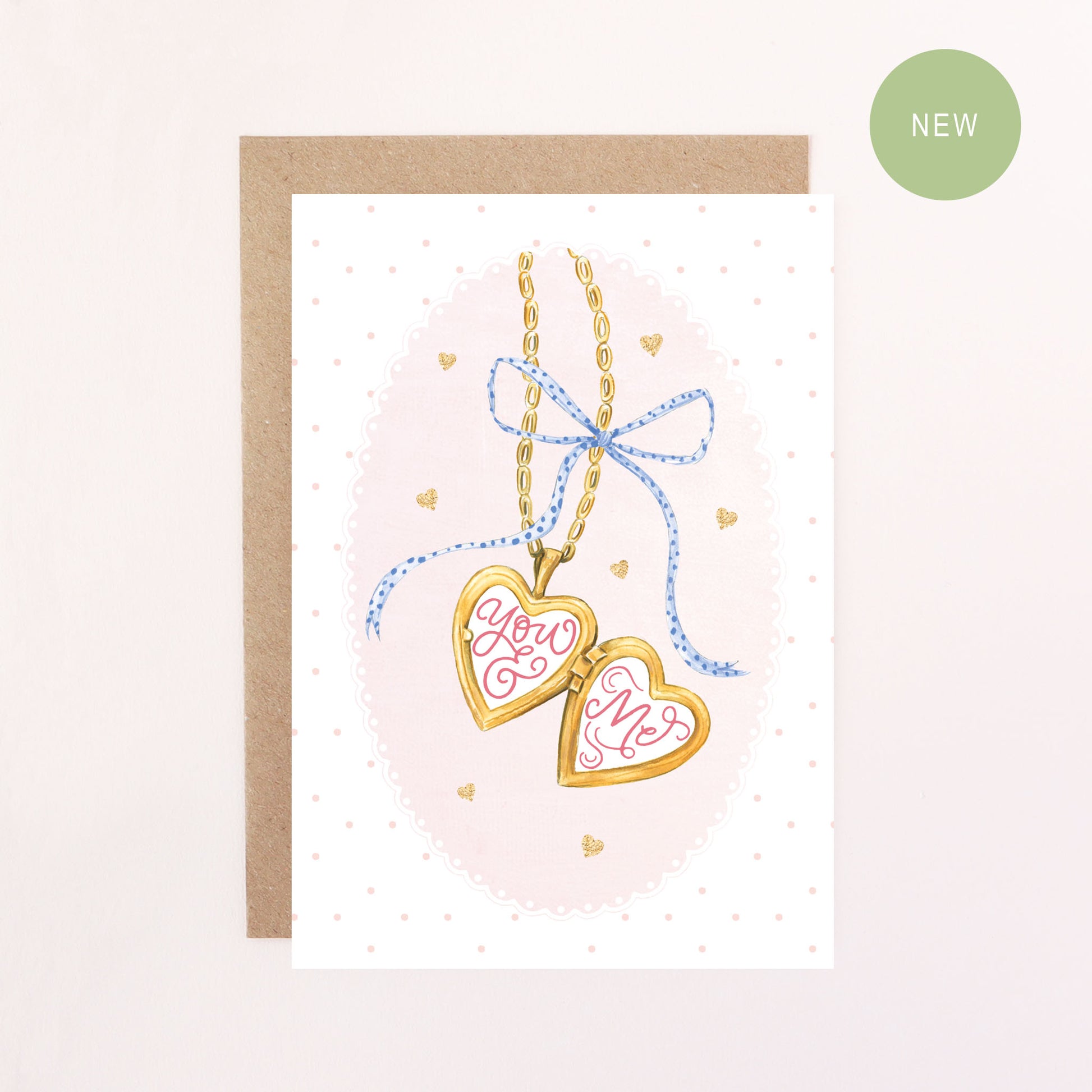 Greeting card with heart-shaped locket and 'You & Me' text on a pink background