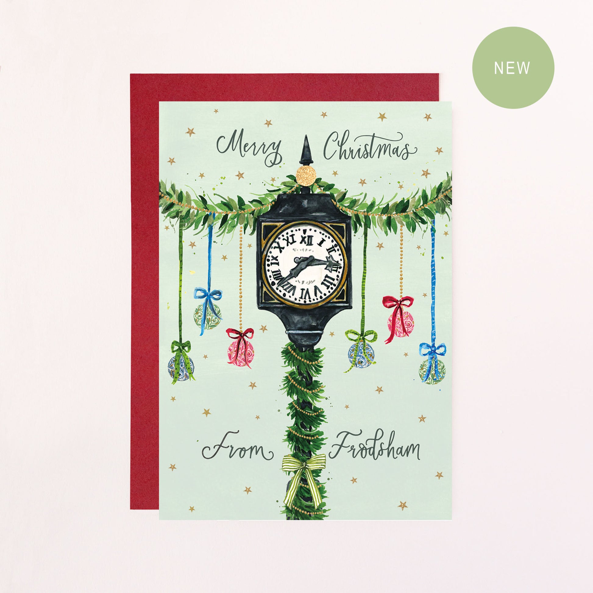 A festive greeting card with green calligraphy text reading 'Merry Christmas From Frodsham' with a drawing of Frodsham Town Clock, baubles, bows and faux glitter stars.