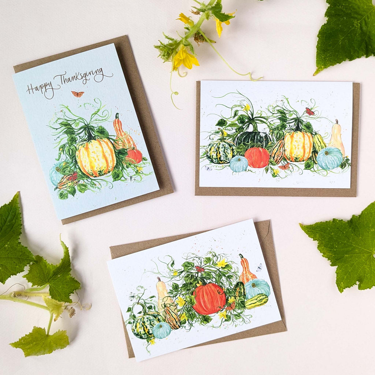 Three Thanksgiving greeting cards with autumn watercolor illustrations of pumpkins, gourds, and vines, arranged on a light background with green leaves and yellow flowers.